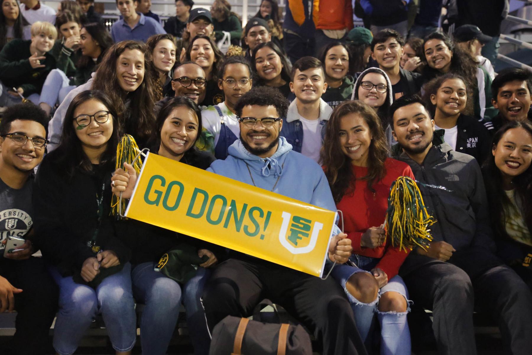 Group of student smiling and holding a GO Dons sign.