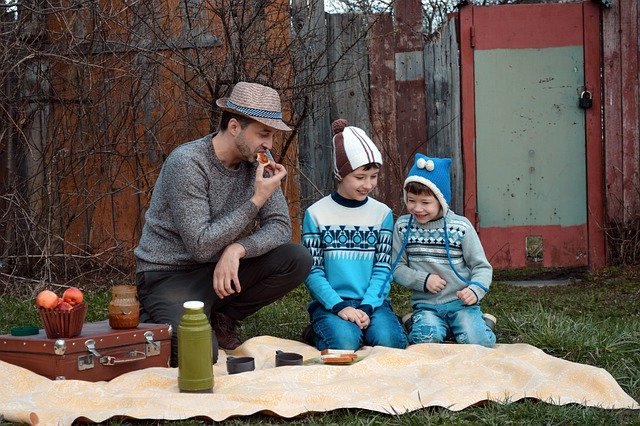 kids and man sitting on blanket