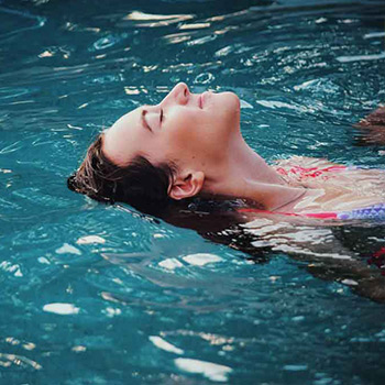 A person floating in a swimming pool.