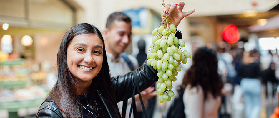 Student holding up a branch of grapes in the San Francisco Ferry Building