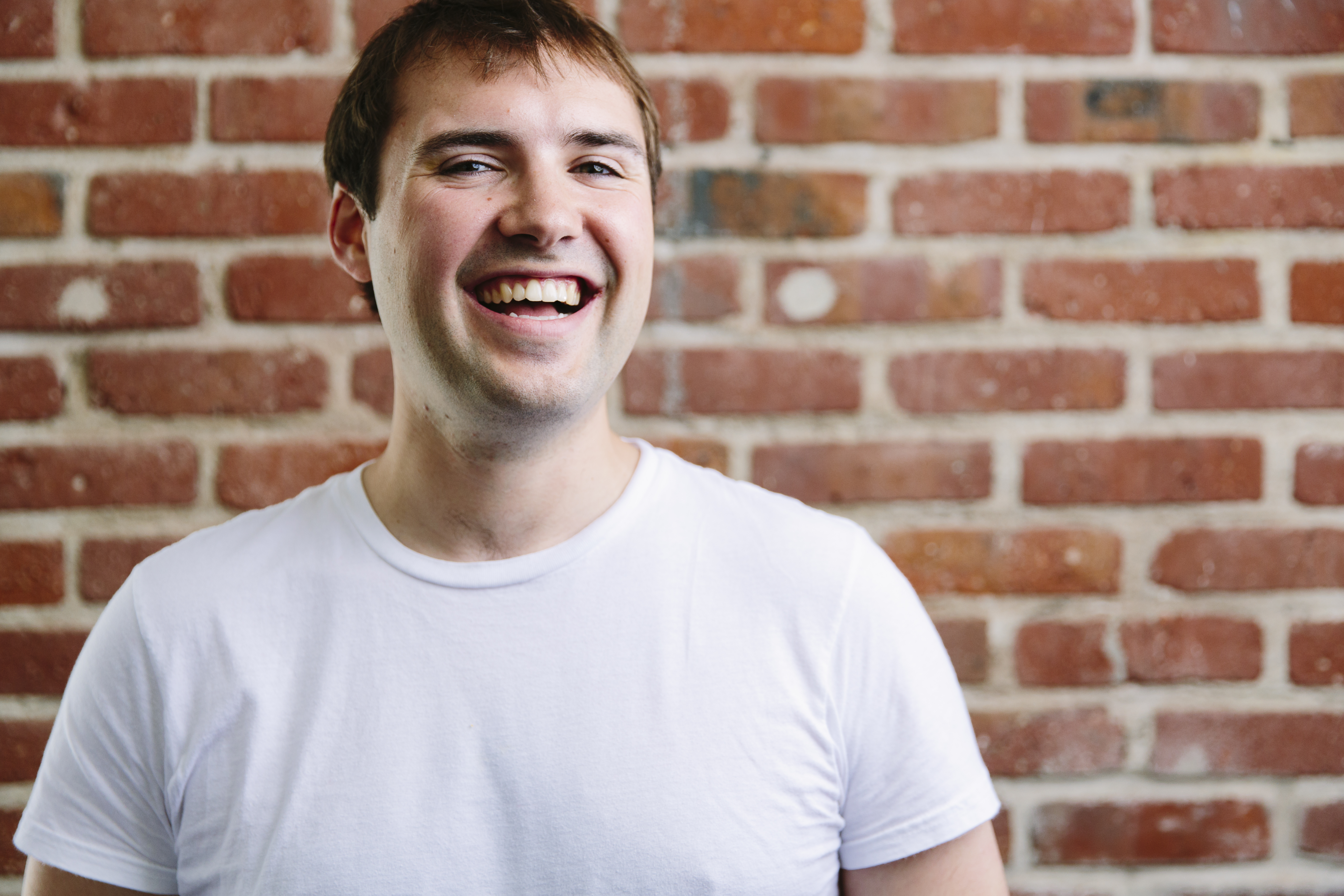 Happy student in front of a brick wall