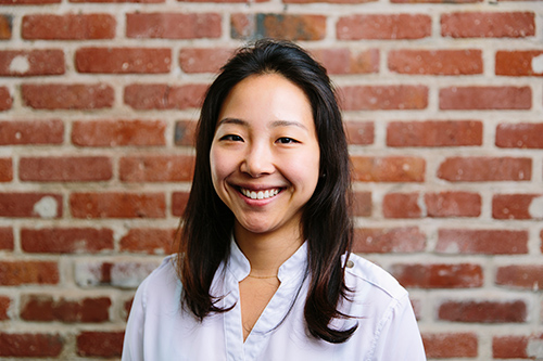 Student standing in front of a brick wall smiling