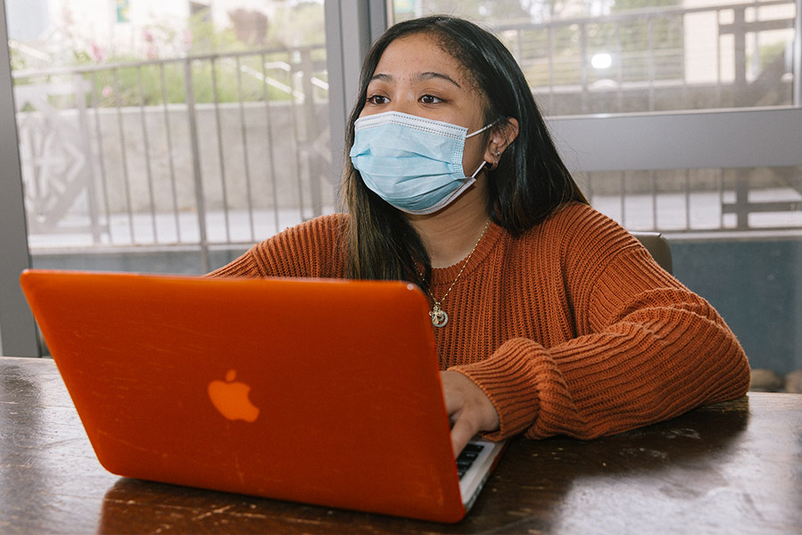 Student in a mask uses a laptop in class