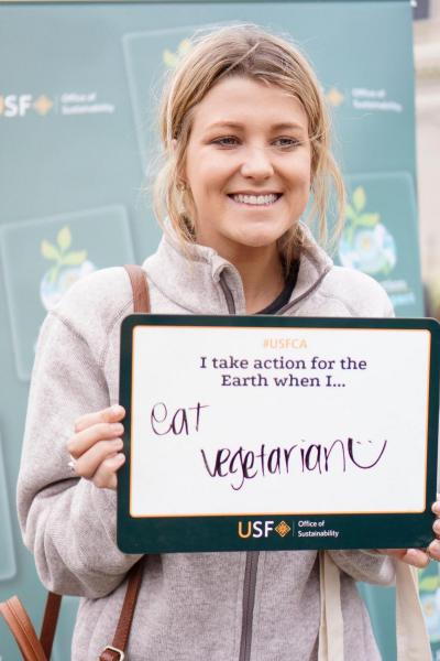 Person holding sign that states &quot;I take action for the Earth when I... eat vegetarian.