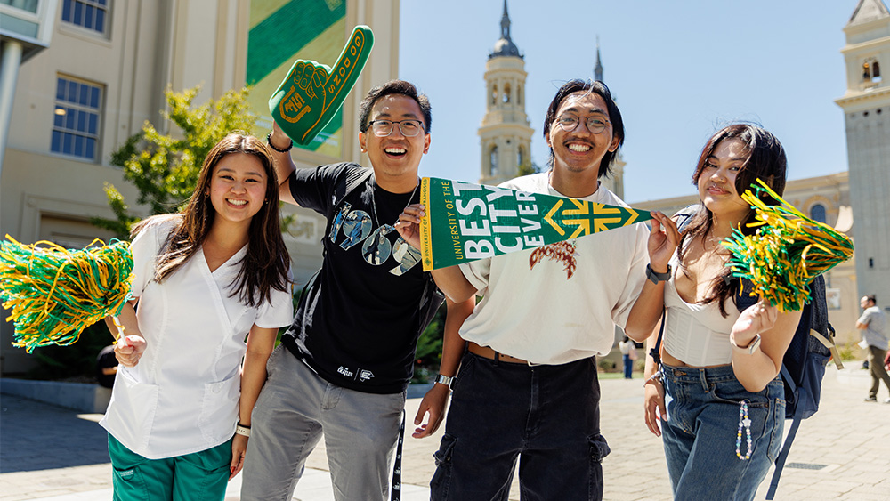 Four students posing with USF merch