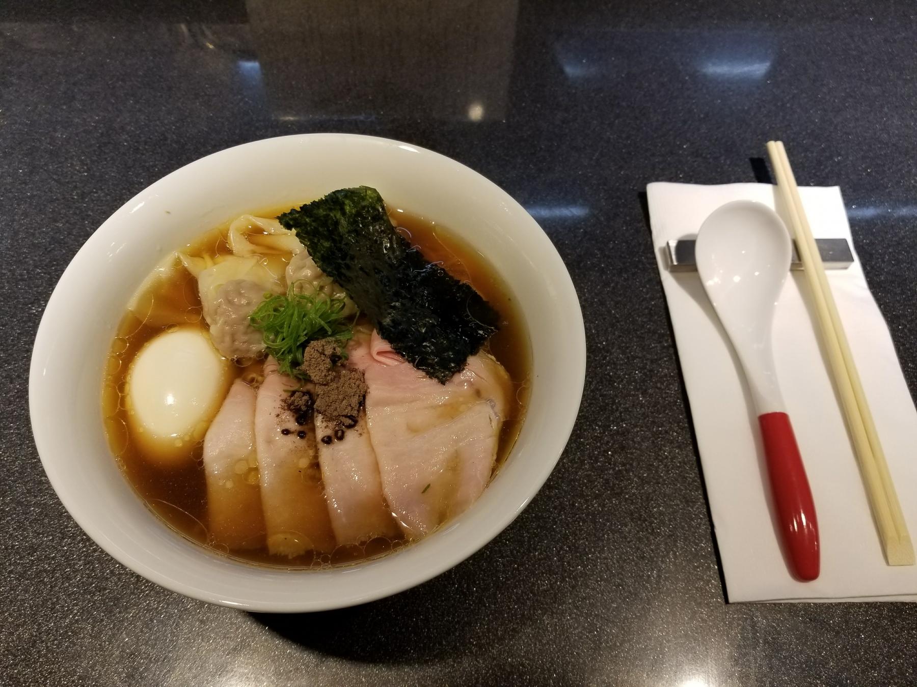 Bowl of ramen beside a spoon and chopsticks 