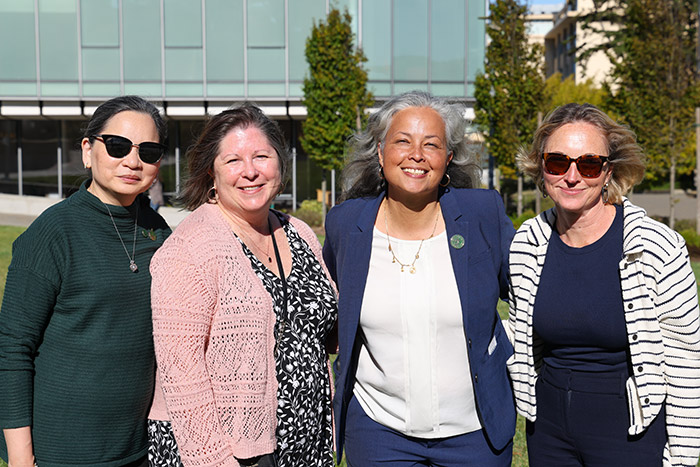 Faculty members smile together for a photo at Gleeson Plaza