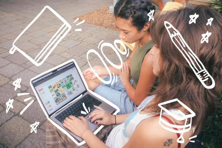"Two students sitting down while looking at a computer"