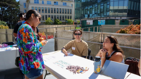 "Student talking to two students at a tabling event"