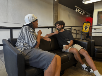 "Two students facing each other on a couch while talking"