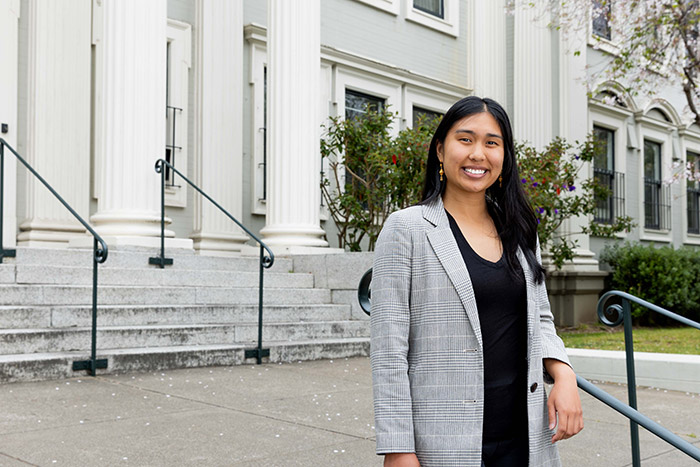 student stands in front of School of Education building