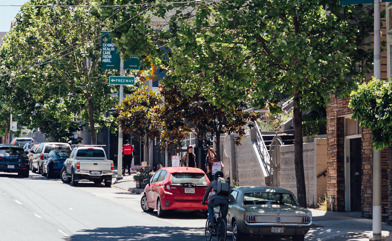 Cars parked on a San Francisco street lined with trees.