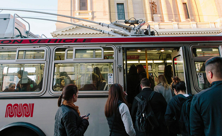 People boarding Muni bus in front of St. Ignatius