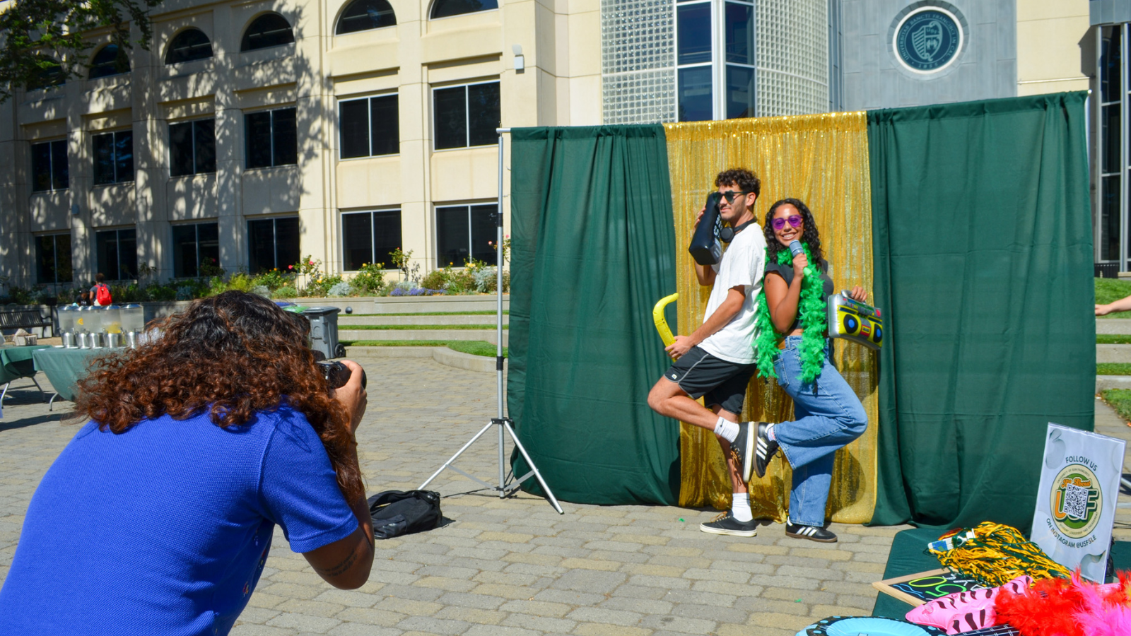 Student photographing students posing in front of backdrop