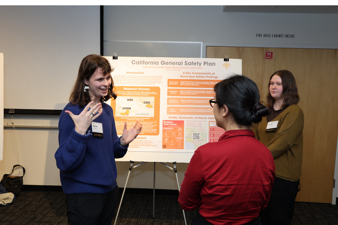 "students discussing project with poster"