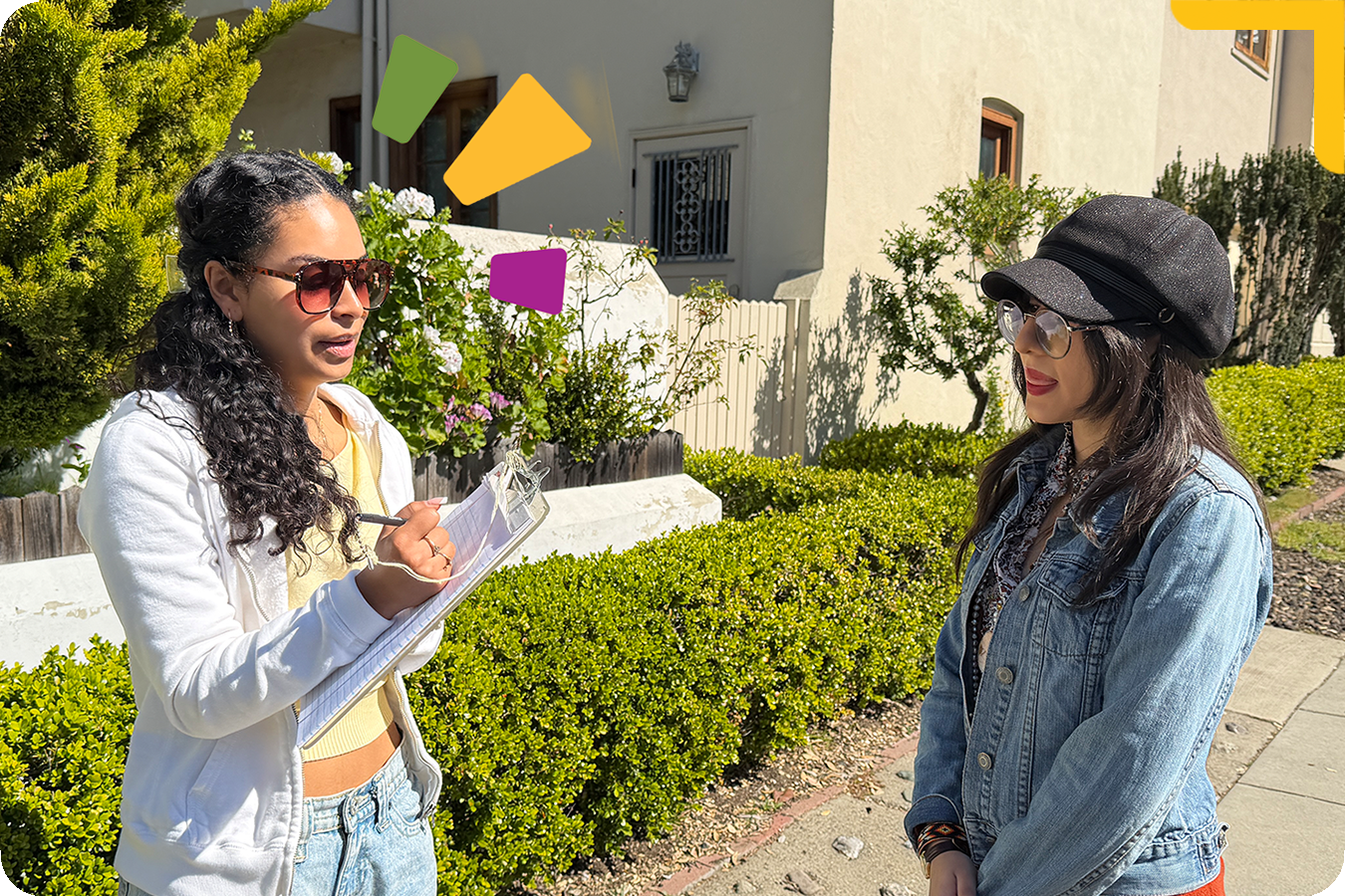"Student holding clipboard interviewing another student"