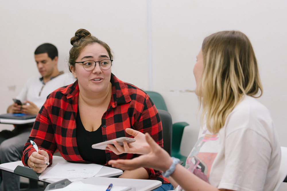 Two students talking at their desks.