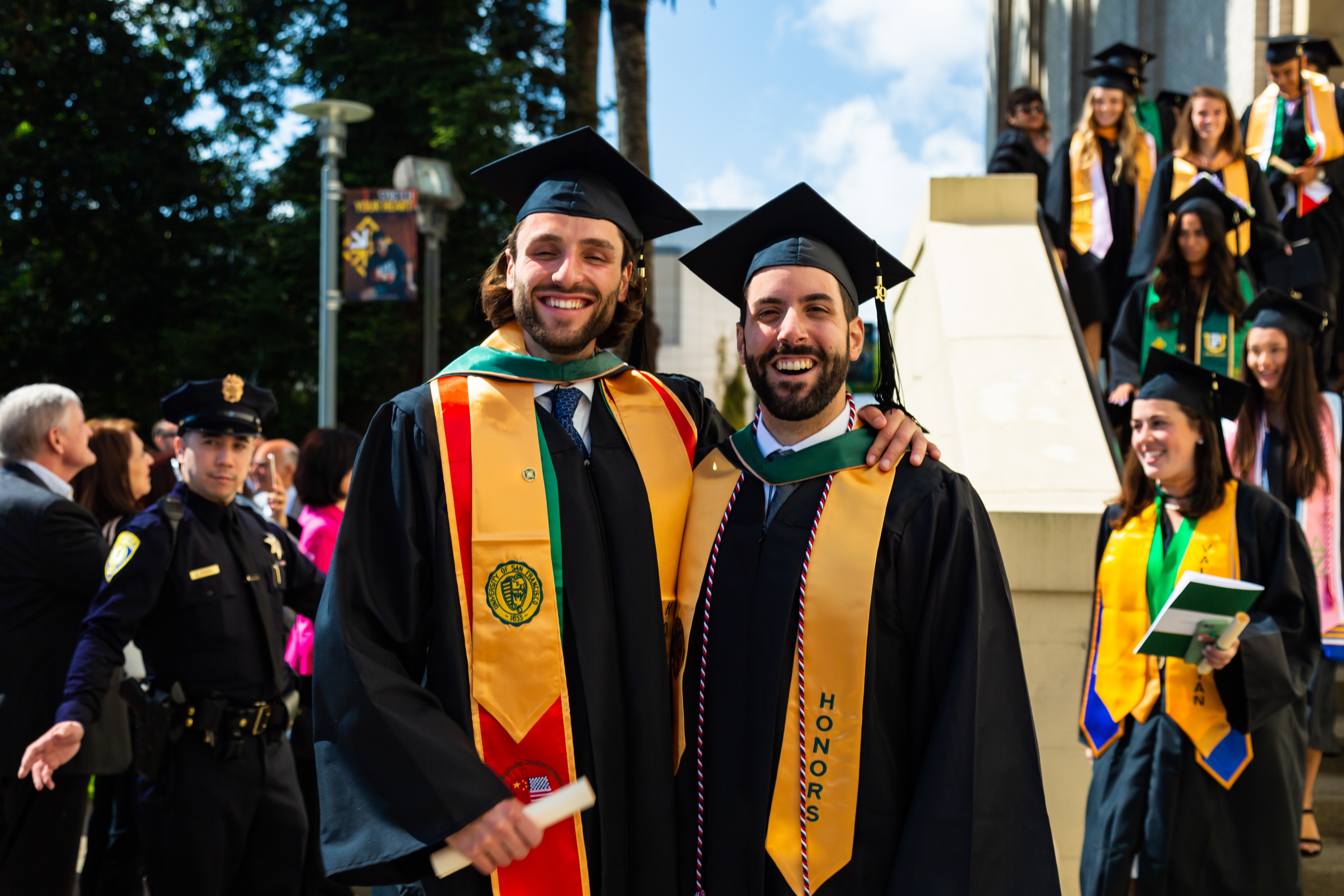 Two alumni posing in their graduation caps and stoles