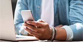 A person holding a mobile phone next to a laptop