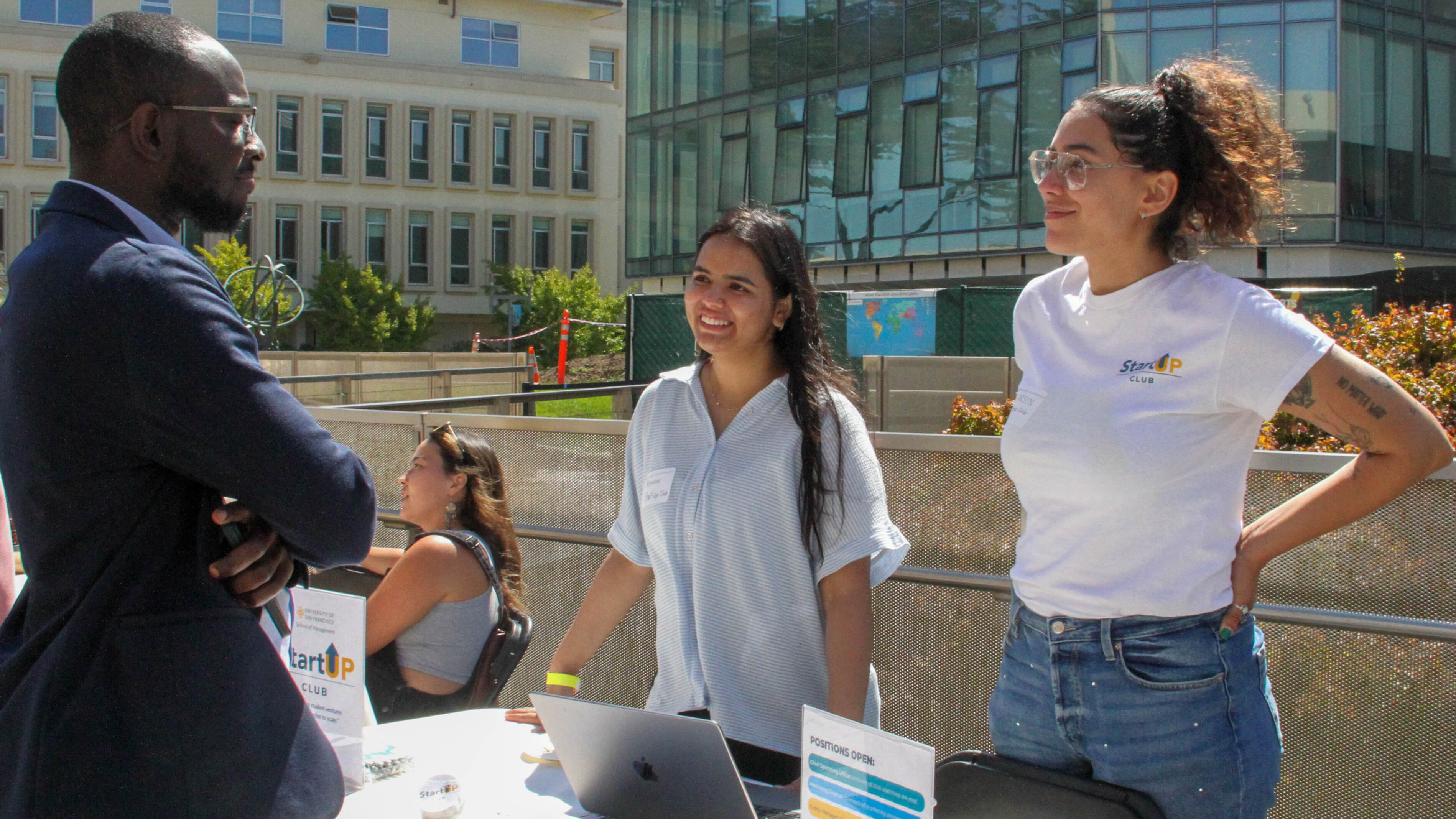 two people tabling and talking to another person