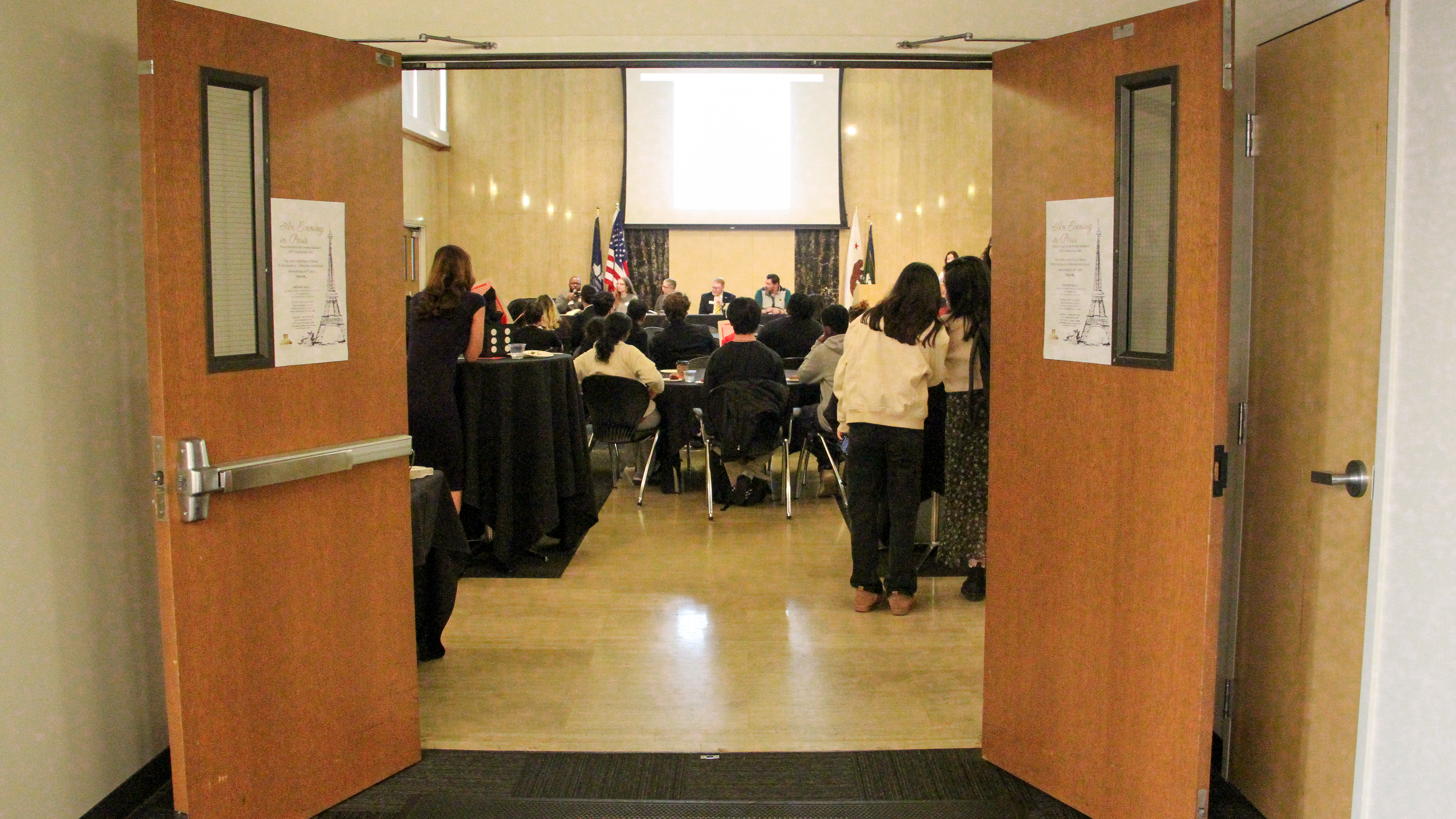 Photo of open doors of Xavier hall in Fromm Hall. Inside are students mingling at one of the ASUSF Senates' town halls.