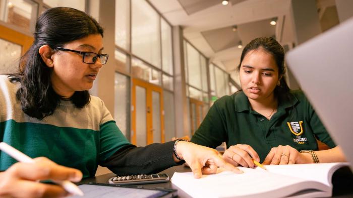 Two students sitting at a laptop.