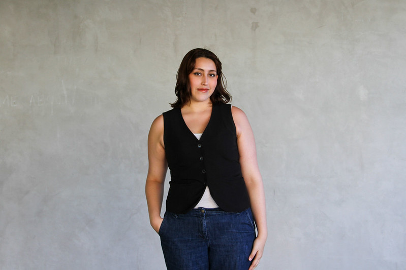 Standing, smiling, with hands in pockets