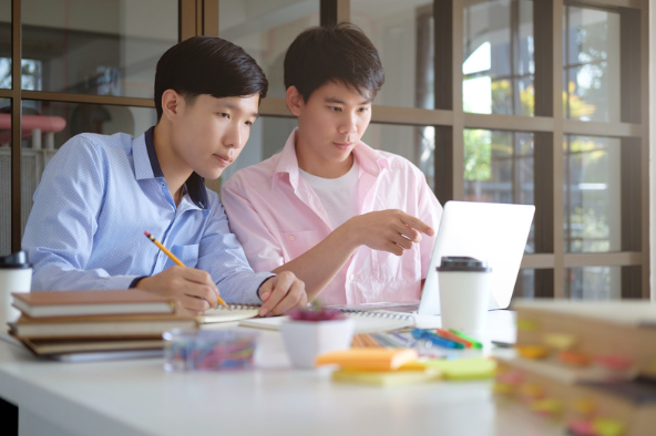 Two students looking at a laptop, working together. 