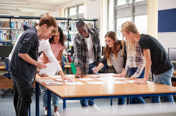 A group of students standing at a table studying.