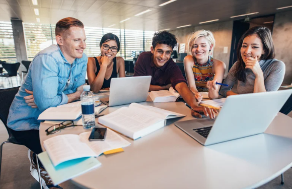 A group of students sitting at a table with their studying material out. 