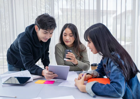 A group of students staring at a tablet. 