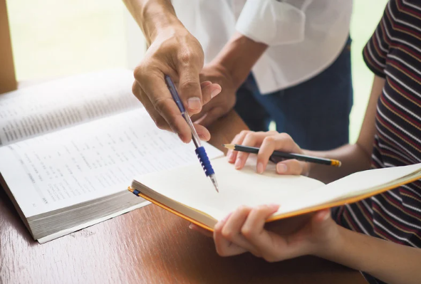 Two individuals looking over a notebook. 