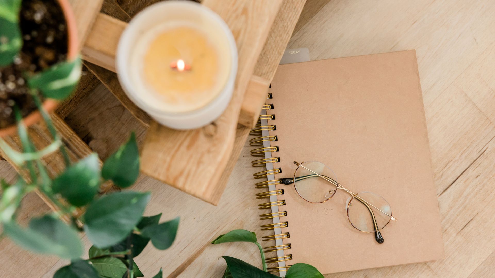 table with candle, leaves, notebook, and glasses