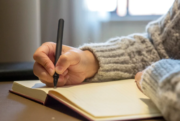 A student writing in a notebook. 