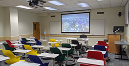 Hyflex classroom with projector screen in front and rolling chairs.