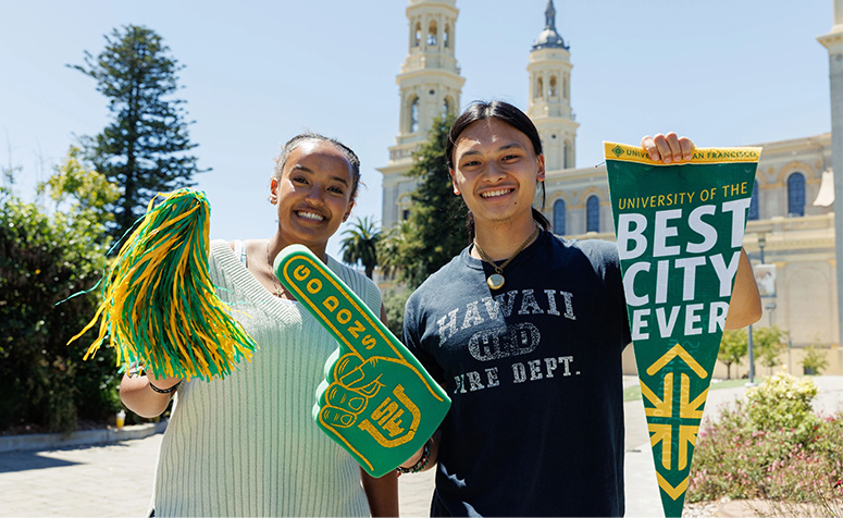 Two USF students posing and holding merch