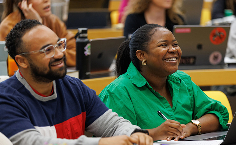 Two students in class smiling