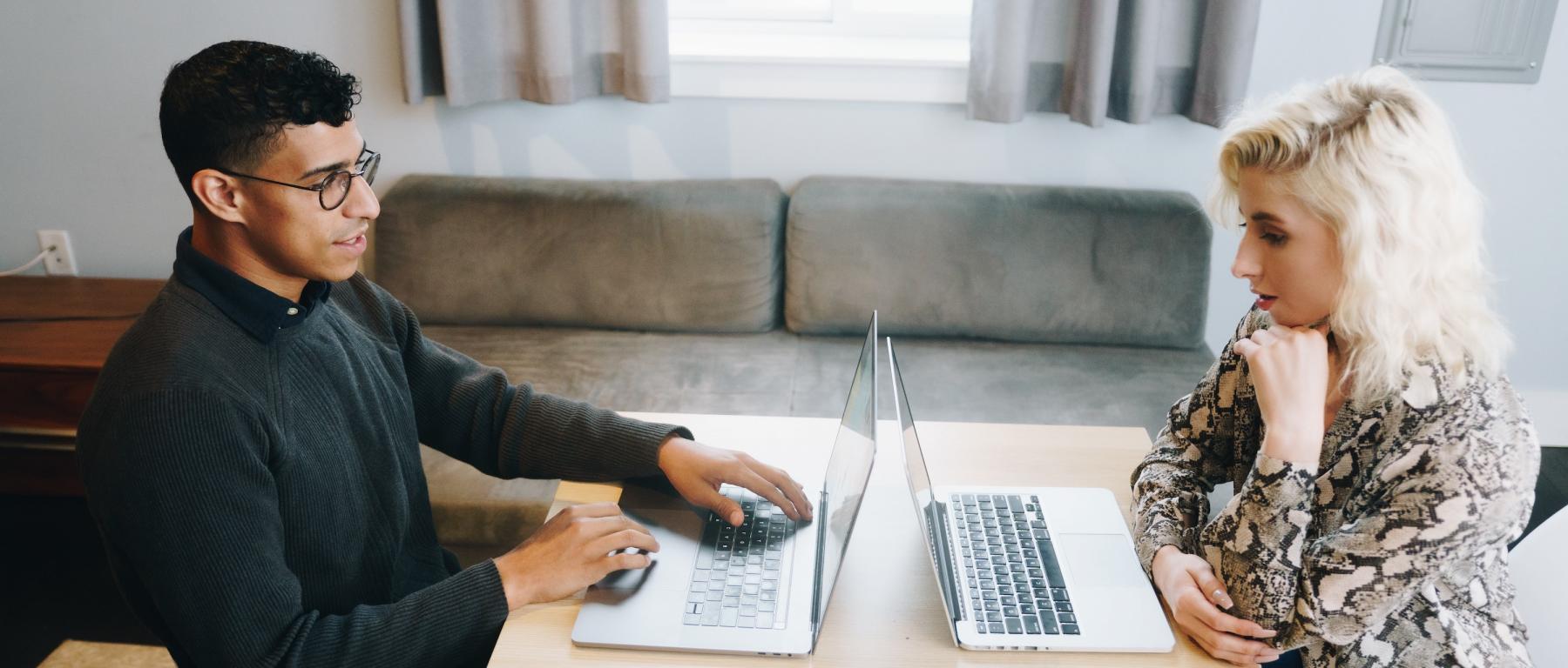 Two people working on laptops at a table