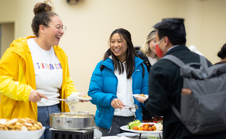 First generation students smiling and serving themselves food