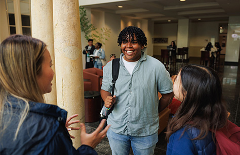 Three USF students smiling and chatting on main campus