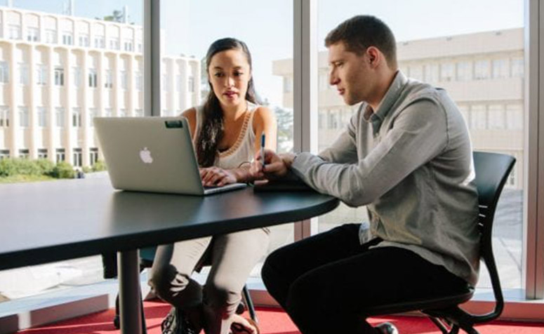 Two students working together on a laptop