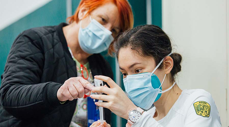 Student and professor using a syringe for vaccines