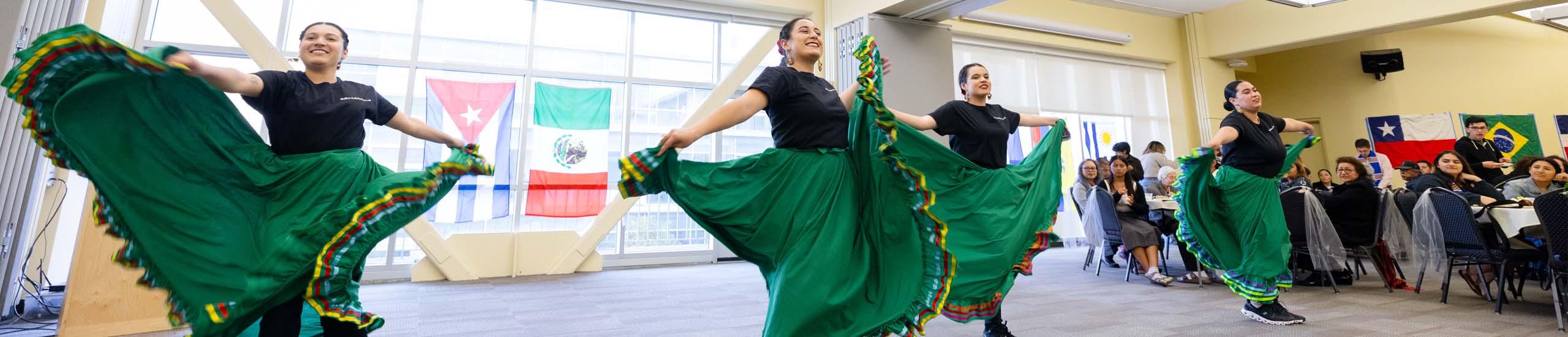 students dancing in traditional Latinx dresses