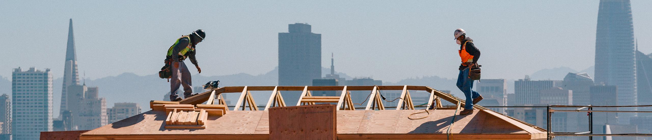 Construction workers on roof of USF building with cityscape in background