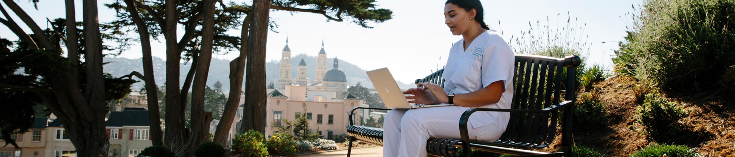 Student sitting on a bench with a laptop