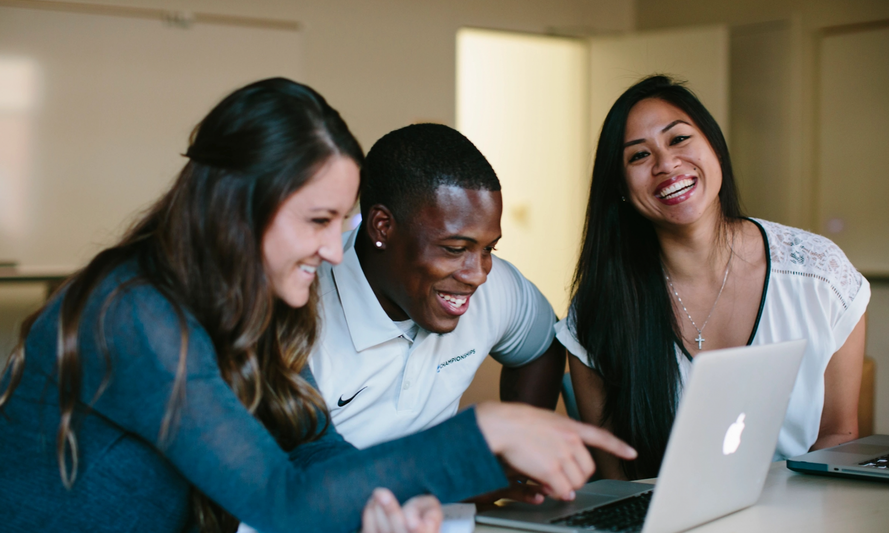 group of students looking at a laptop together