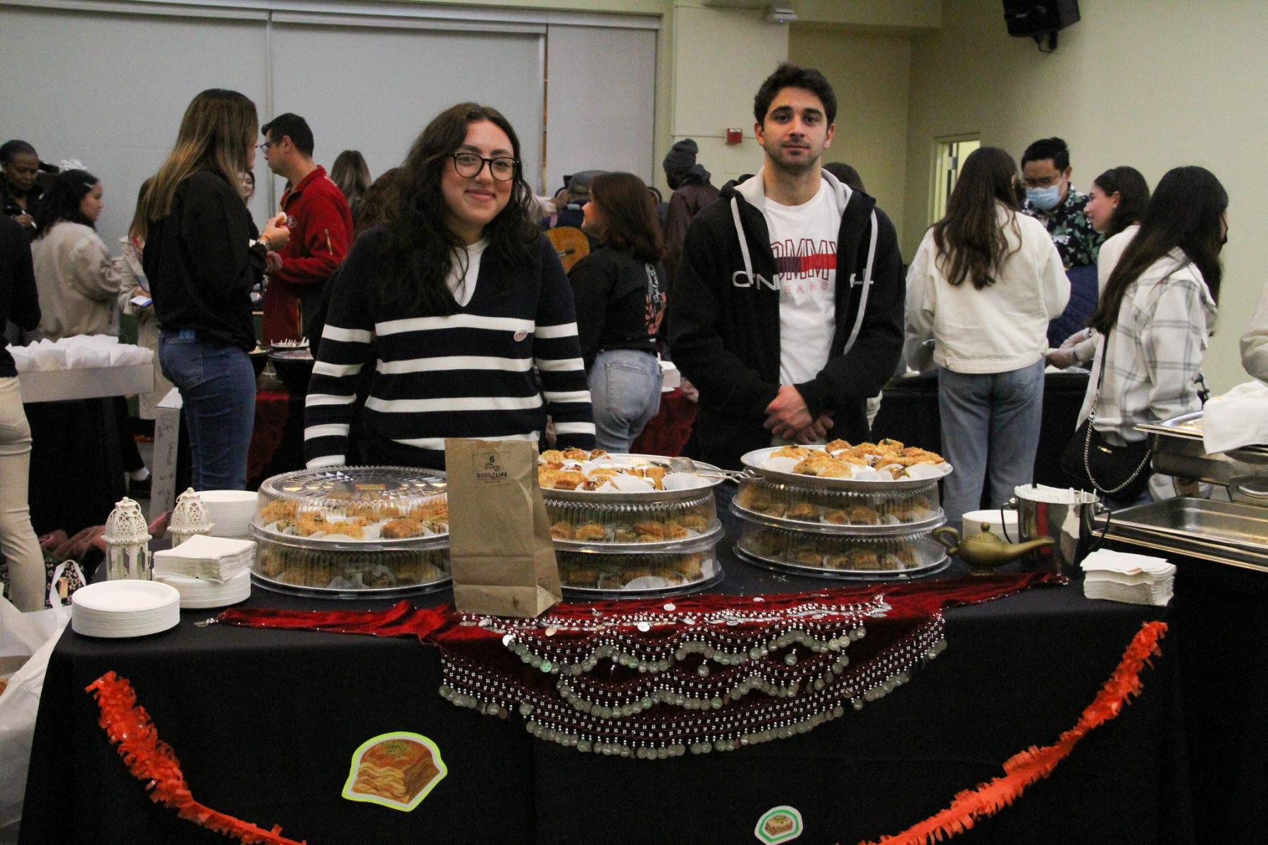 2 USF students standing behind a table full of food pastries at the 2022 Culturescape food festival