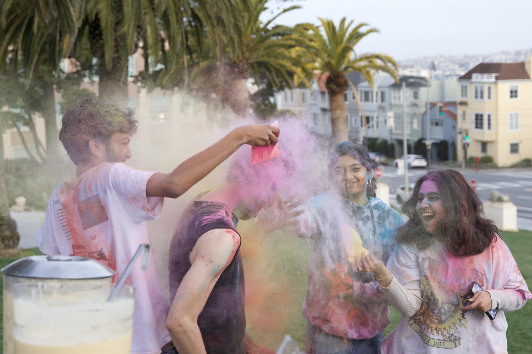 USF students participating in Holi, playfully throwing colored powders onto one another 