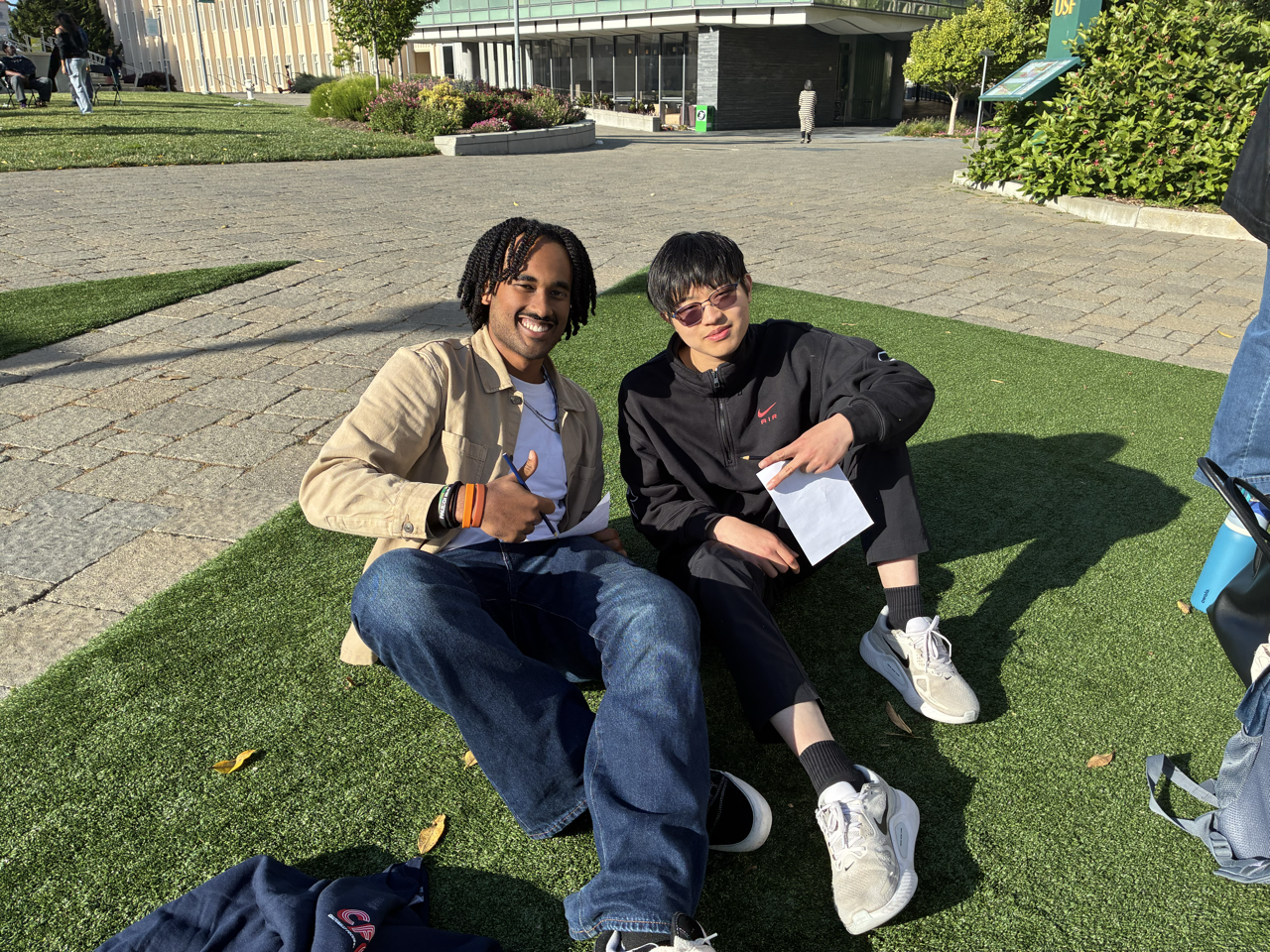 "Two CFCC members smiling while sitting on the grass"