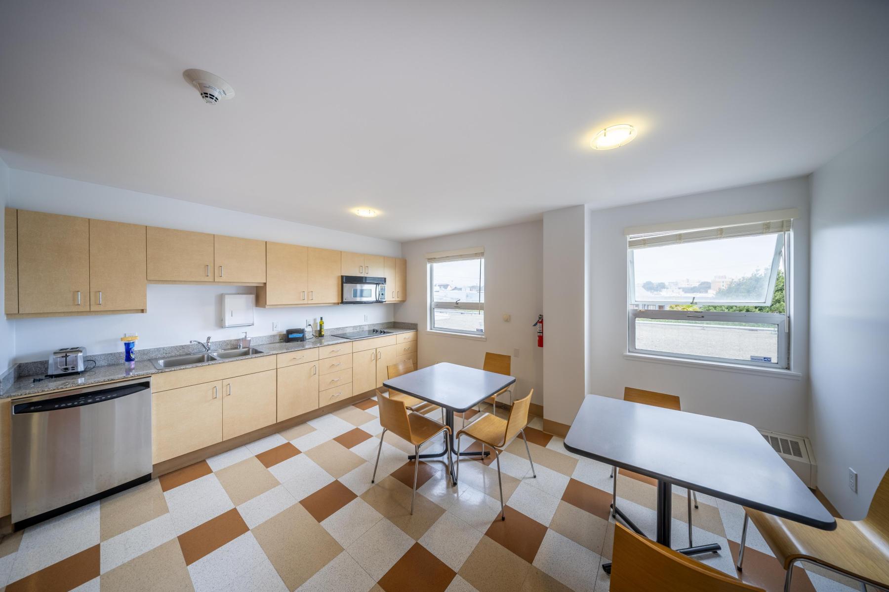 Dining area with two tables and a kitchen counter with stove, dishwasher, and sink